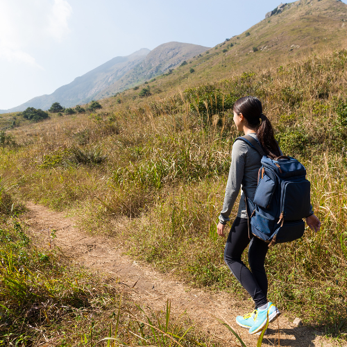 リュックとトレッキングポールを手に登山を楽しむ女性